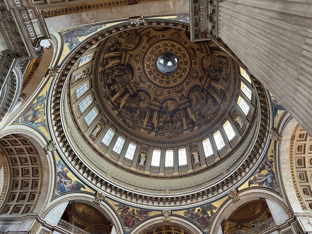 A detailed view of an ornate dome interior with intricate frescoes, arches, and windows greets visitors on the London Christian Tour. The central artwork, depicting historical figures and elaborate designs, creates a grand architectural impression.