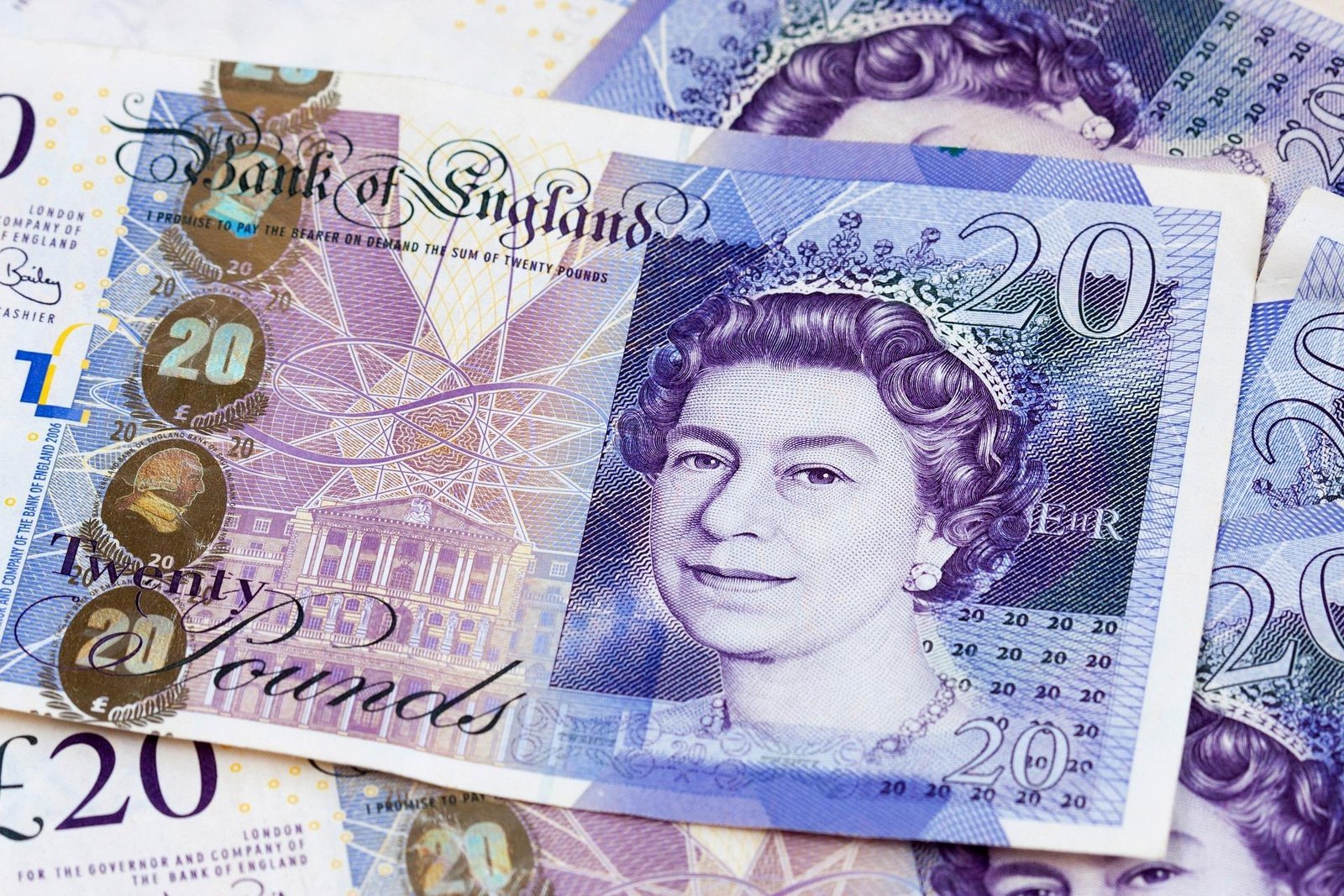 A close-up of British twenty pound banknotes, featuring a portrait of Queen Elizabeth II and architectural designs, with overlapping notes in the background—perfect for planning your next adventure eating in London.